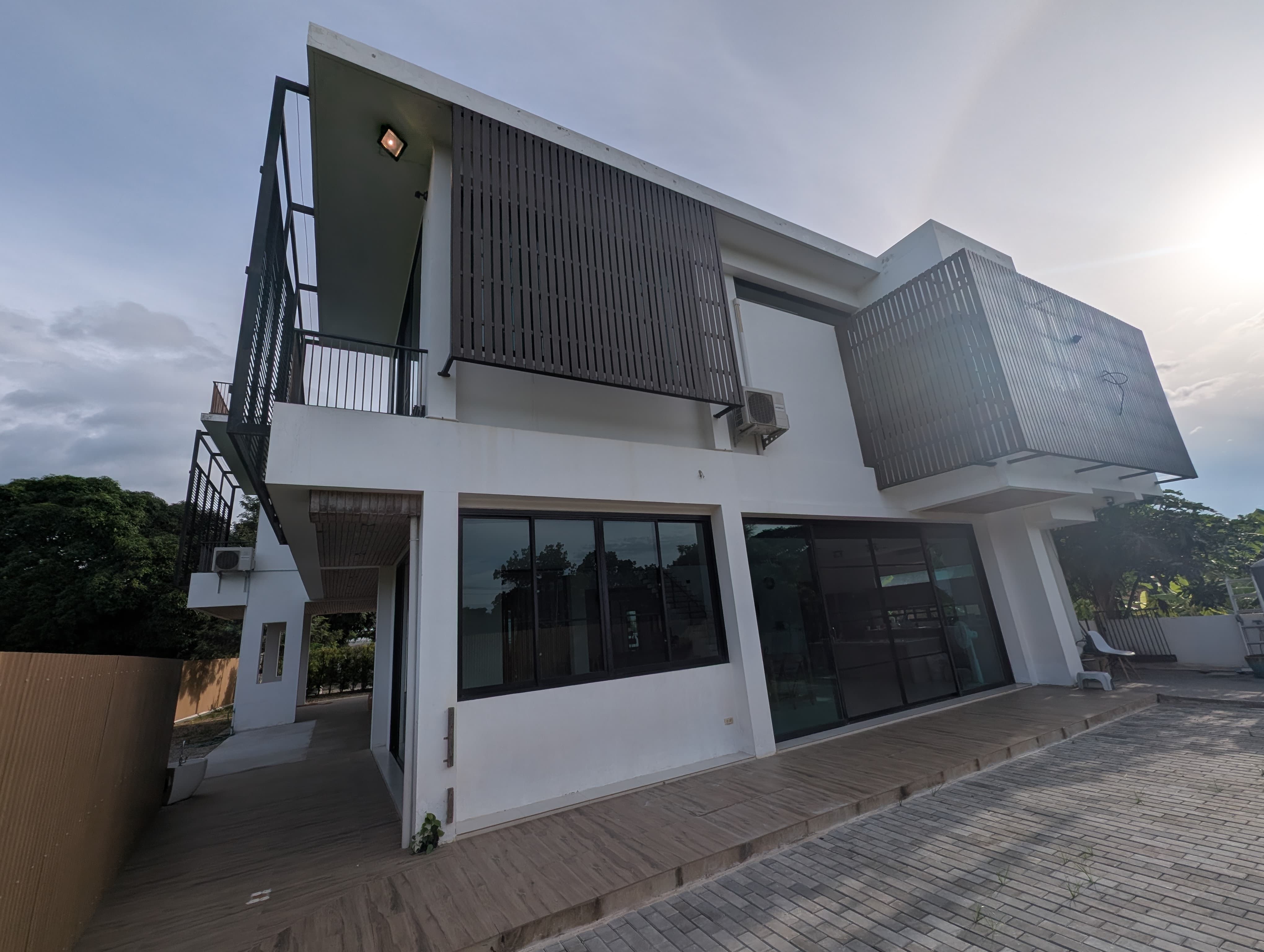 Two-storey white house with screened balconies and a paved outdoor area