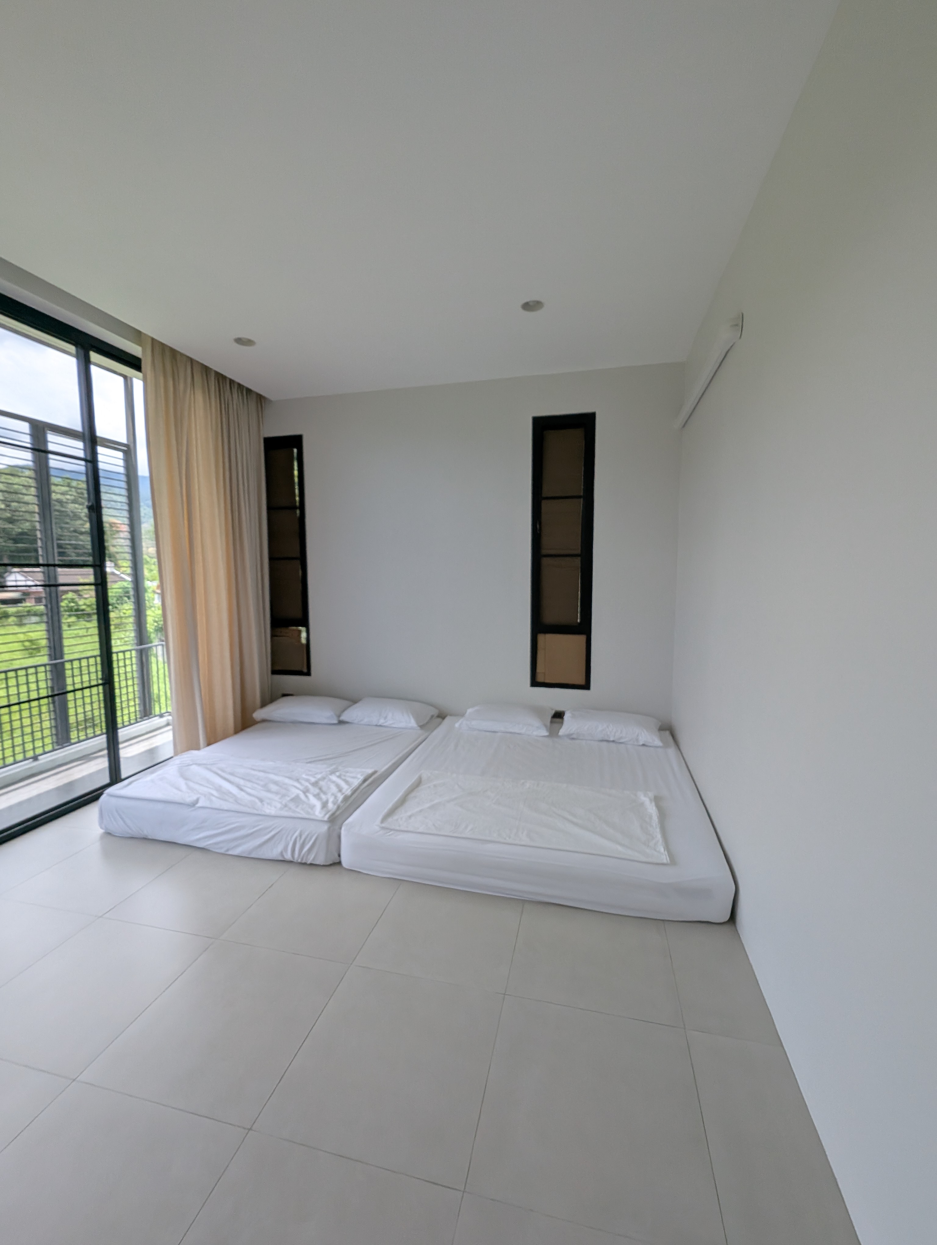 Bedroom with mattresses, white walls and balcony doors