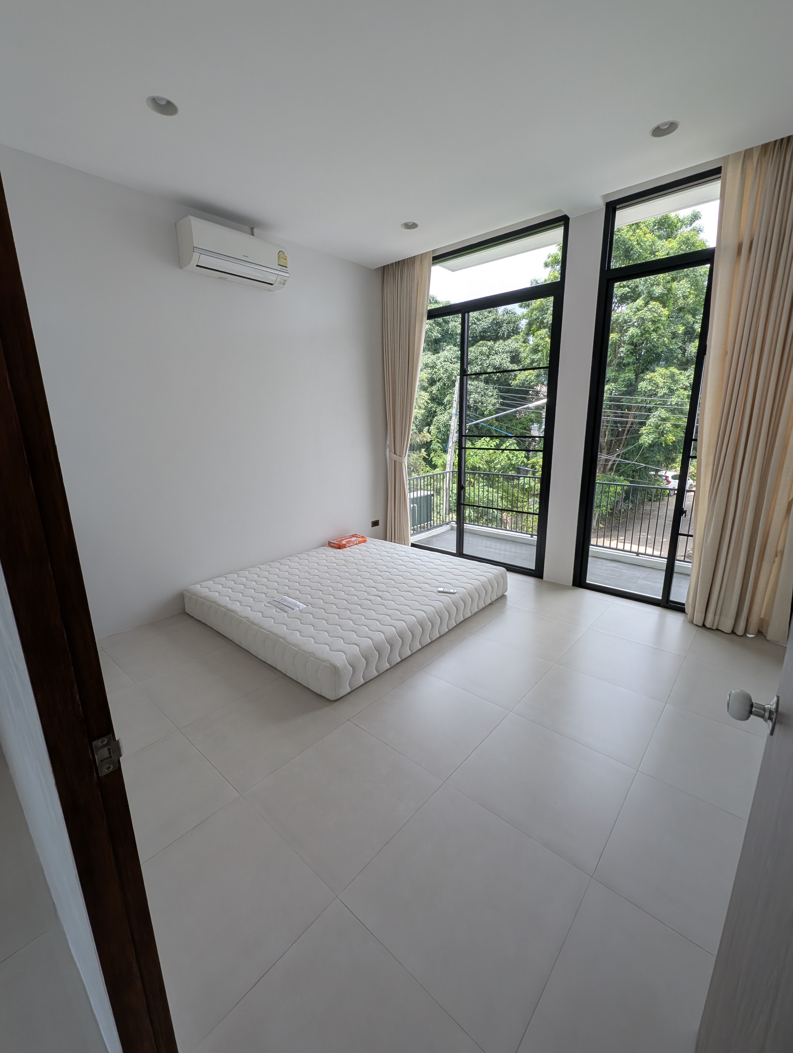 Another bedroom with mattresses and windows facing greenery